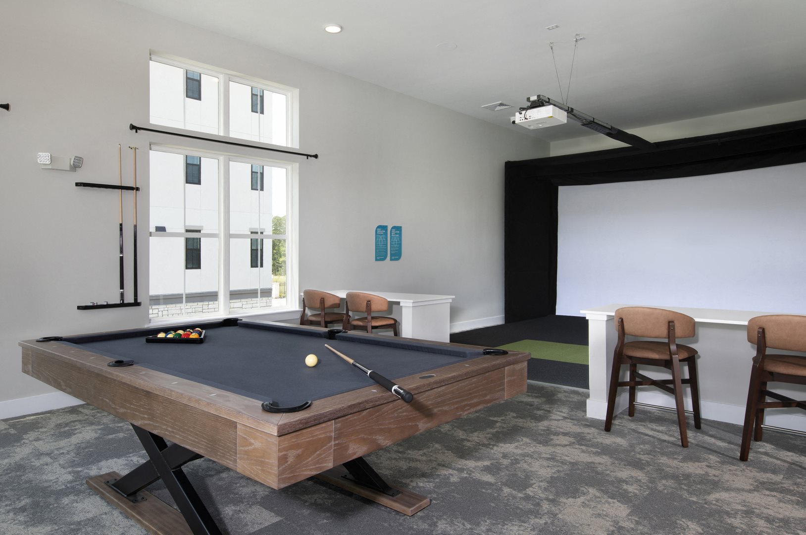 a game room with a golf simulator and pool table at a senior apartment community